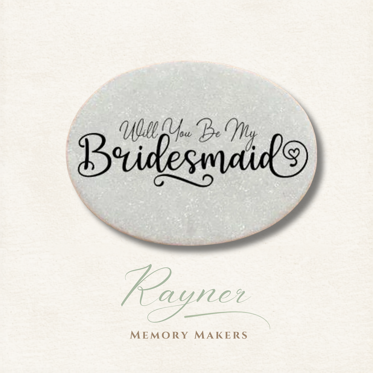 Oval pebble with 'Will You Be My Bridesmaid' text on a light gray background