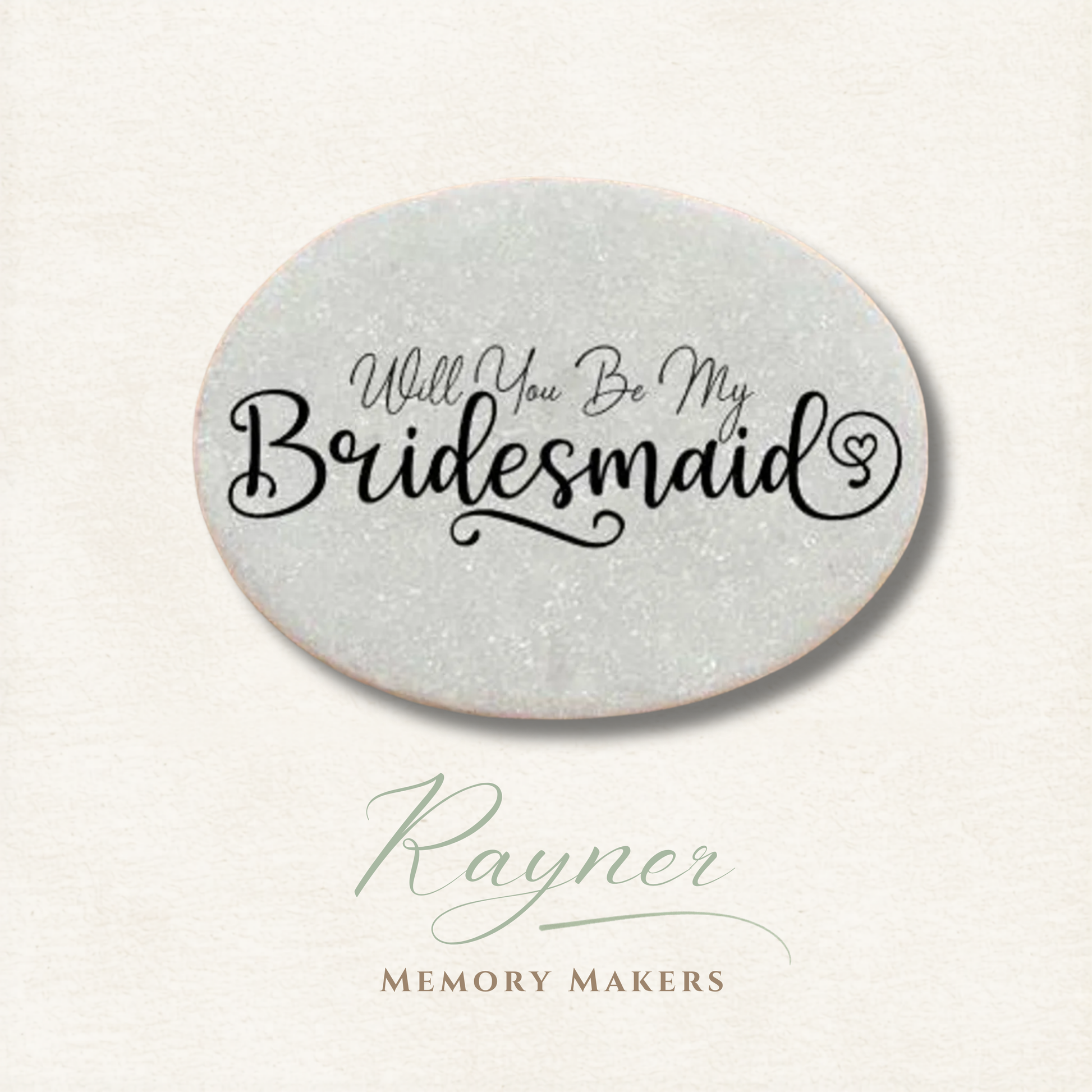 Oval pebble with 'Will You Be My Bridesmaid' text on a light gray background