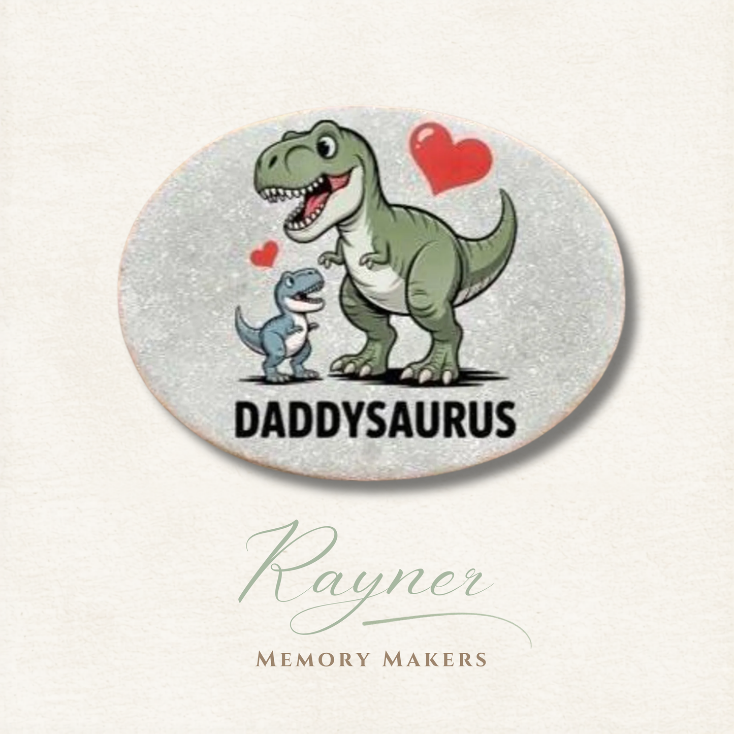 Oval coaster with cartoon dinosaurs and 'Daddysaurus' text on a light background, featuring the brand 'Rayner Memory Makers'.